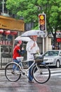 Chinese elderly with bike and umbrella on a rainy street, Shanghai, China